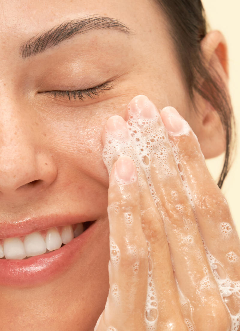 Woman rubbing Gentle Hydrating Cleanser on her cheek