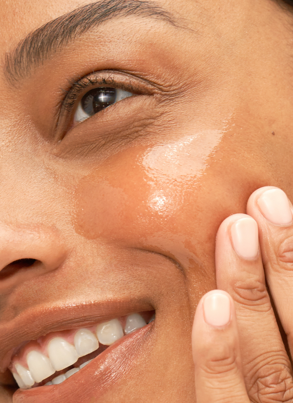 Woman rubbing Intense Replenishing Serum product on cheek